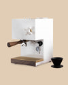 modern sleek white espresso machine appliance with wood portafilter, brass fittings, glass water tank, porcelain steam knob side view