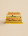 eight yellow-hued stacked books with stories about travel, art, photography, and food
