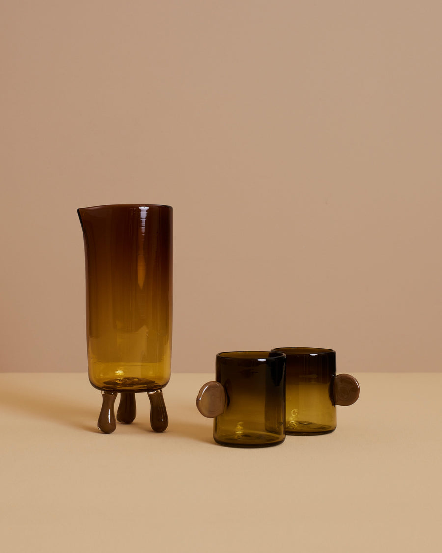 artisanal hand blown footed glass carafe and two glasses with handles in amber and tobacco colors