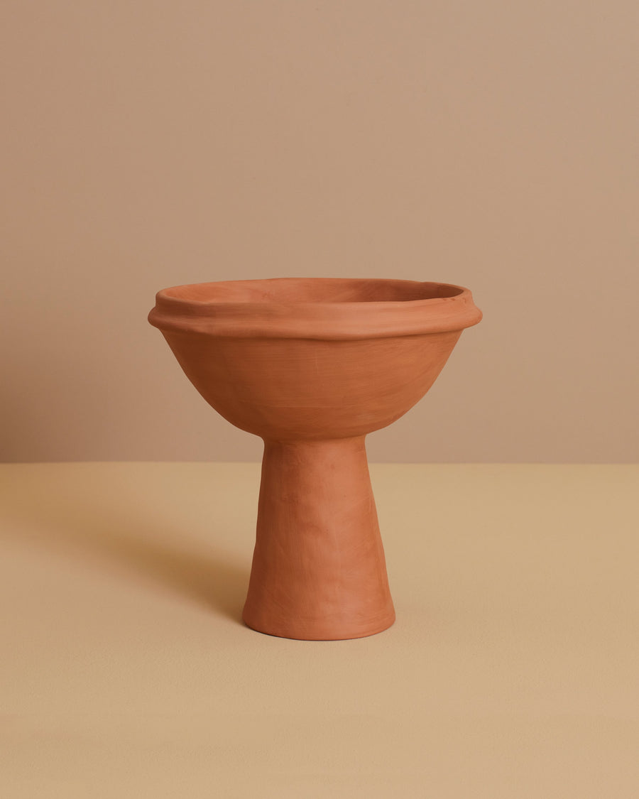 stylized image of terracotta handmade Mediterranean one-piece elevated bowl on cone stoneware fruit platter