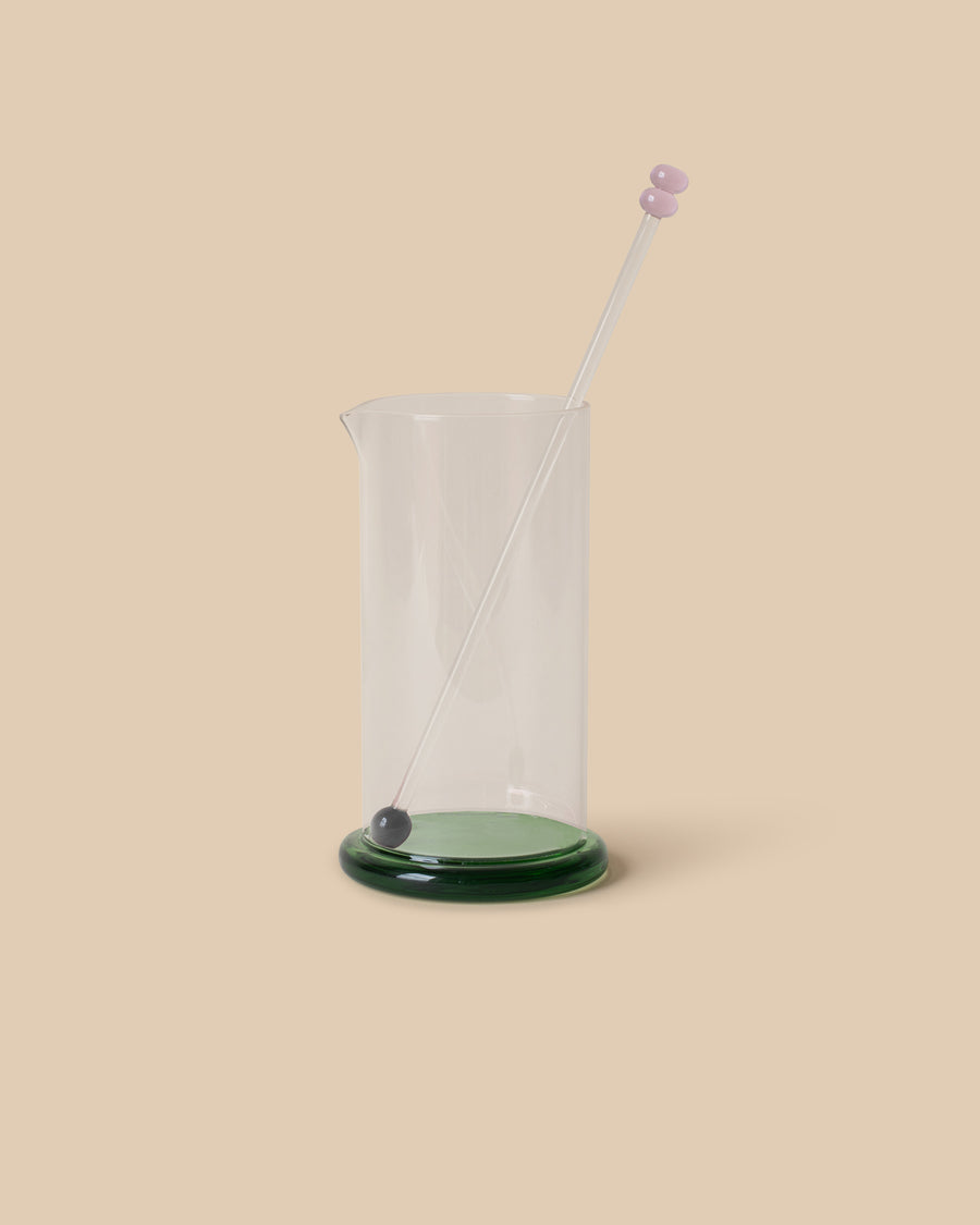 Sophie Lou Jacobsen Fritter Cocktail Mixer, a borosilicate glass mixer with a vibrant green base and contrasting stir stick, perfect for cocktails or juices.
