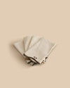 Set of four Twist Napkins by Sophie Lou Jacobsen, featuring natural linen with a wavy edge and contrasting embroidered details in terre, bordeaux, ocre, and olive.