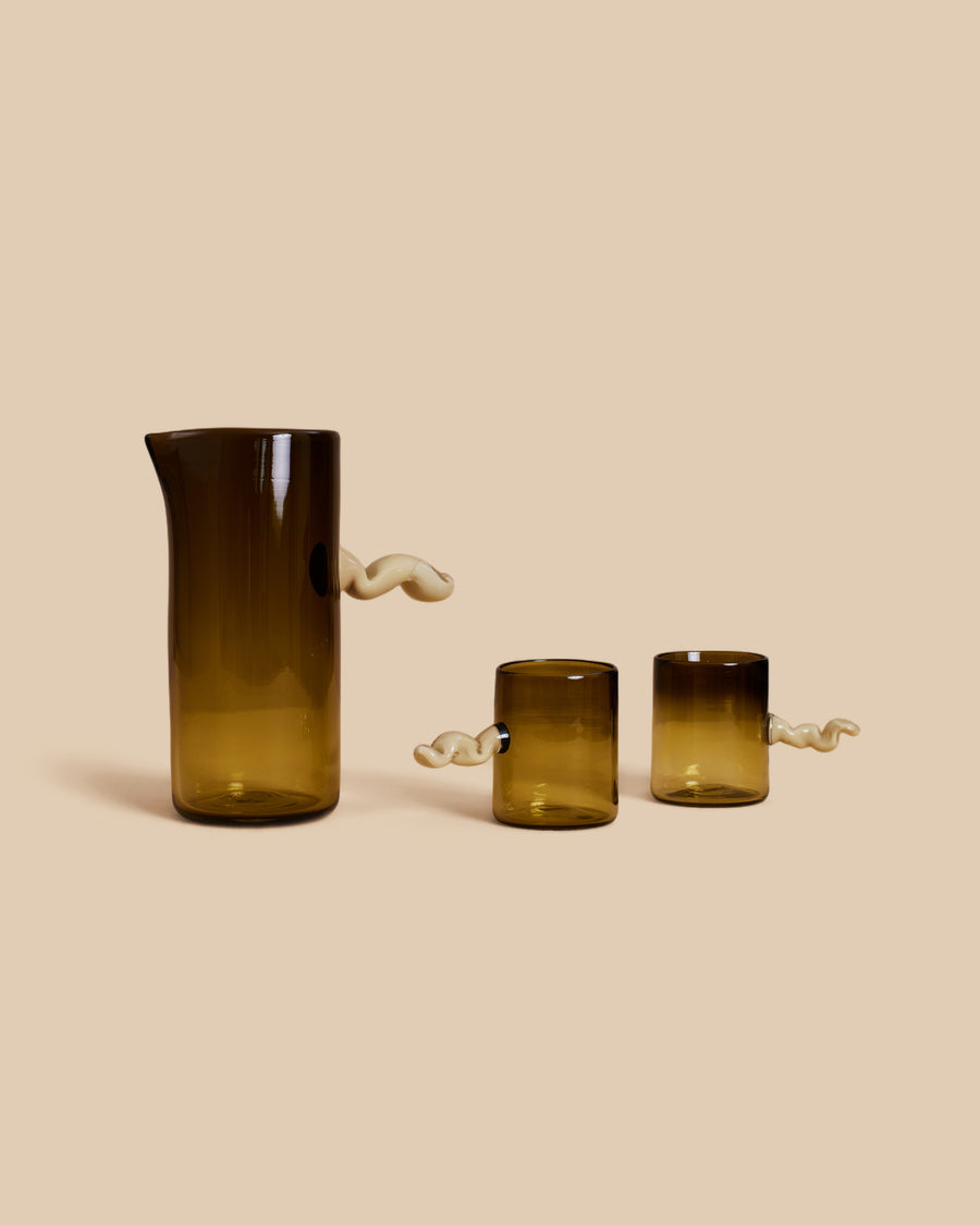 Wiggle Carafe and Wiggle Cup Set by Sticky Glass in smoke and cream, a tall olive carafe and two cups, each with a white squiggle handle