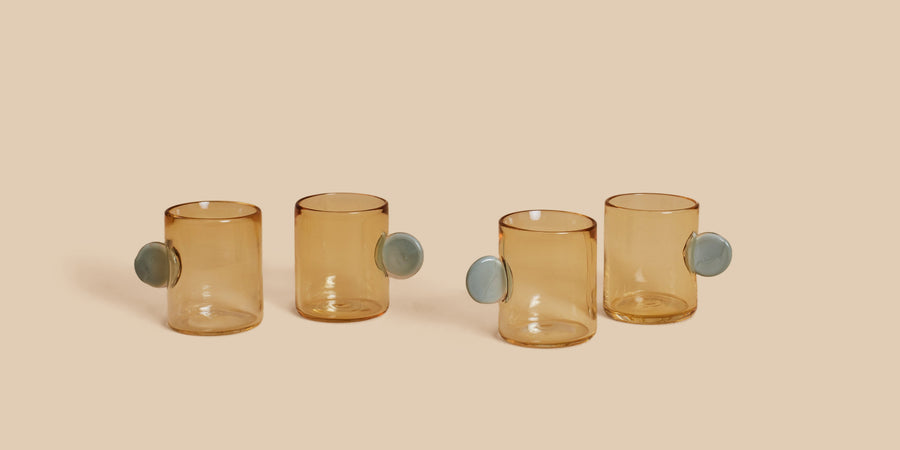 Dot Glass Set by Sticky Glass in whiskey and grey, four hand-blown pale amber cups with blue-grey disc handles
