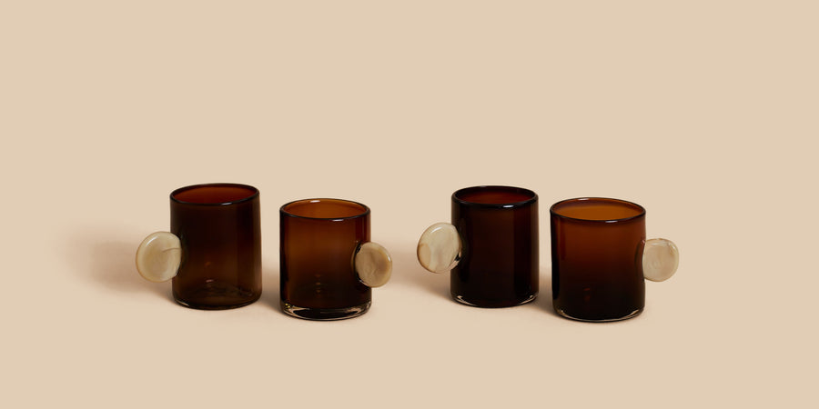 Dot Glass Set by Sticky Glass in amber and cream, four hand-blown cups in dark amber with pale cream disc handles