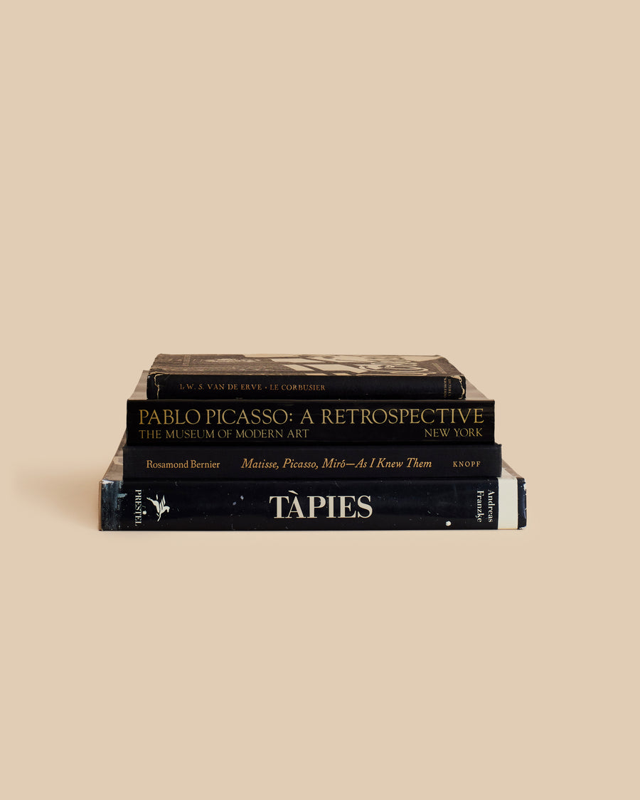  four book stack with black covers of famous painters and architects in dark neutral colors