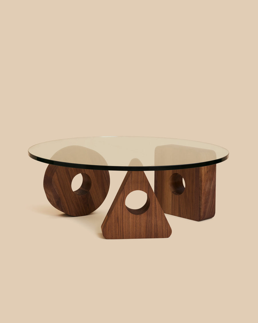  round glass coffee table on a base of three walnut wood geometric shapes