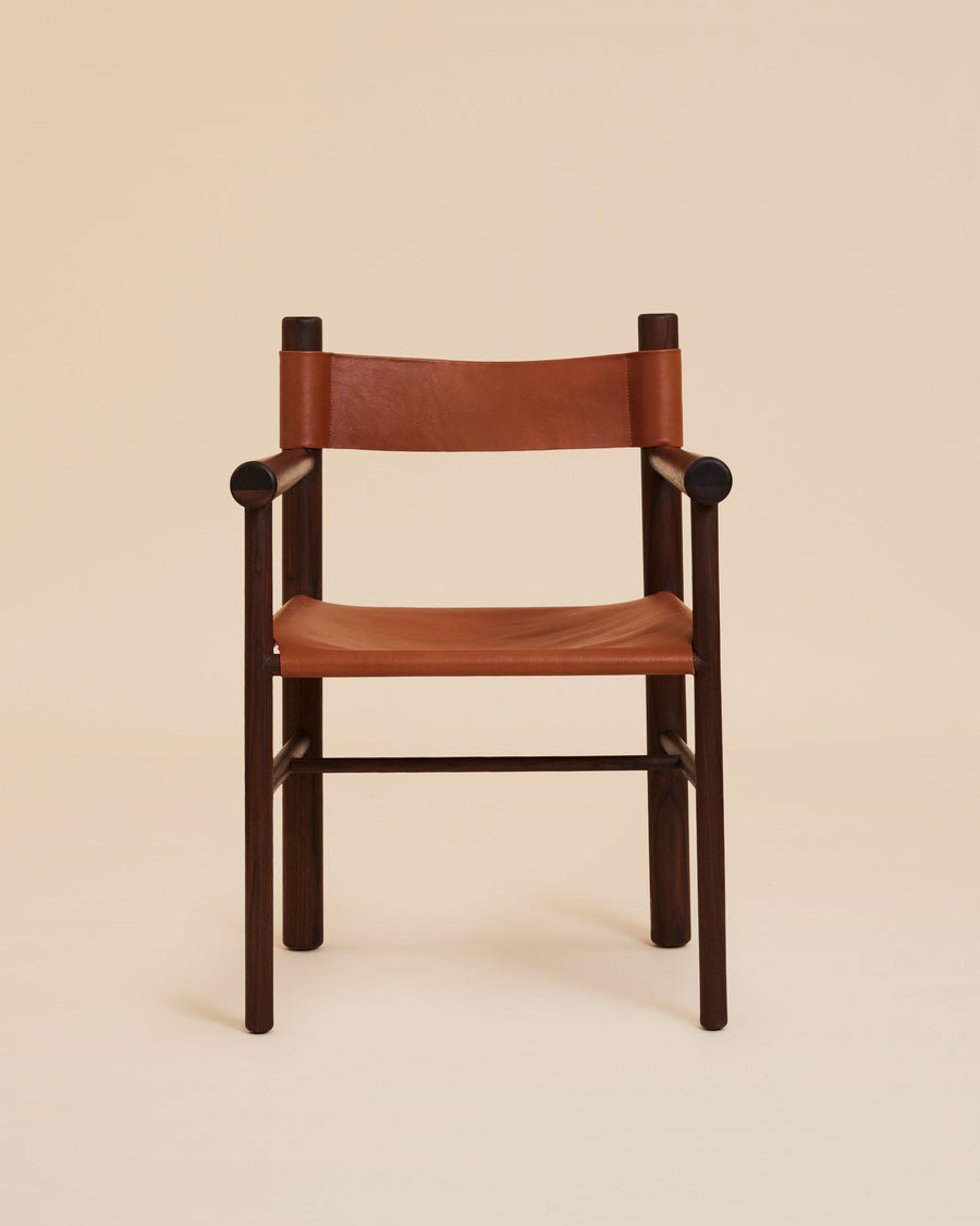 stylized image of turned walnut wood accent armchair with cognac leather sling seat and backrest
