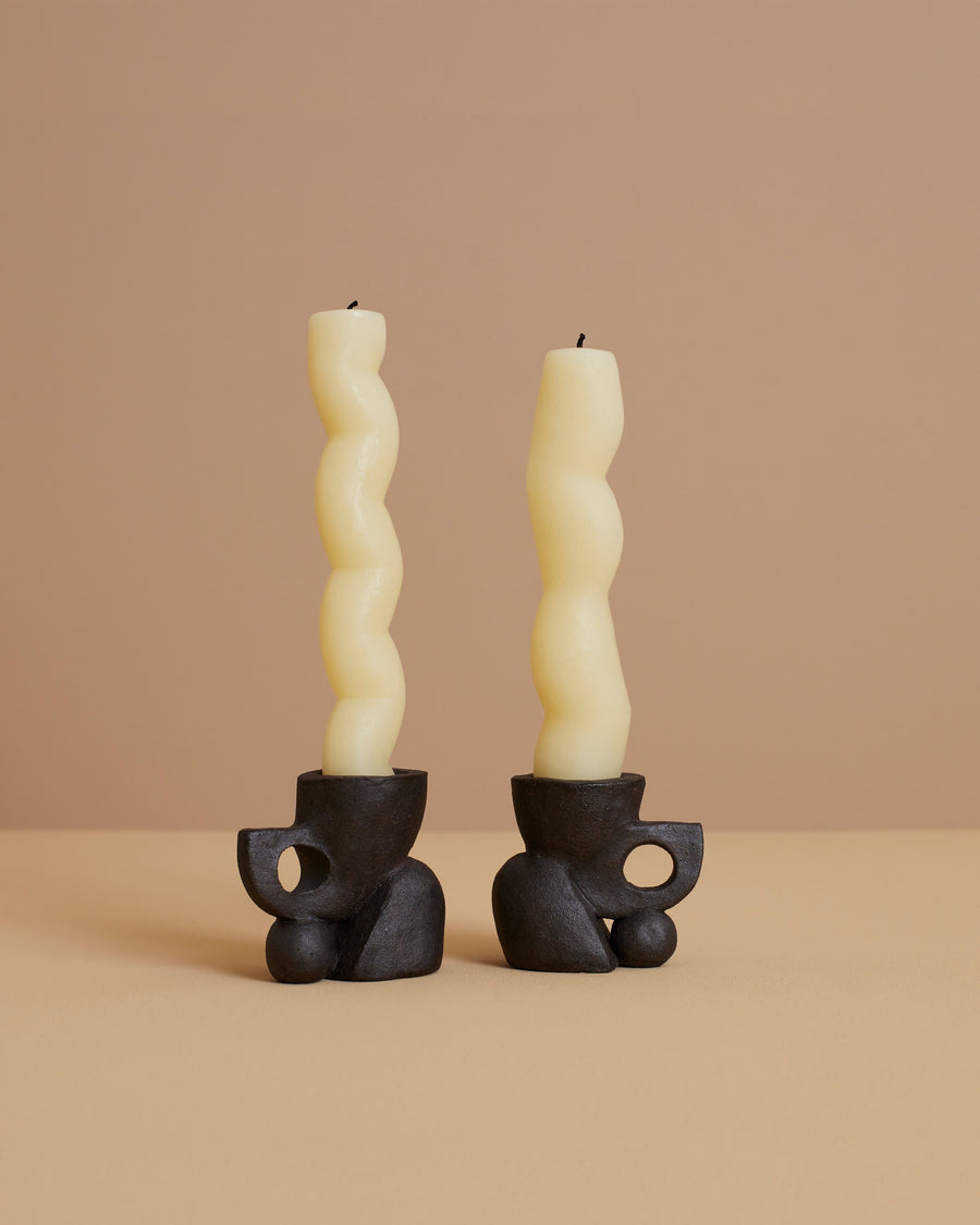 black ancient indigenous-inspired sculptural candlestick holder set and two natural colored sculptural candles
