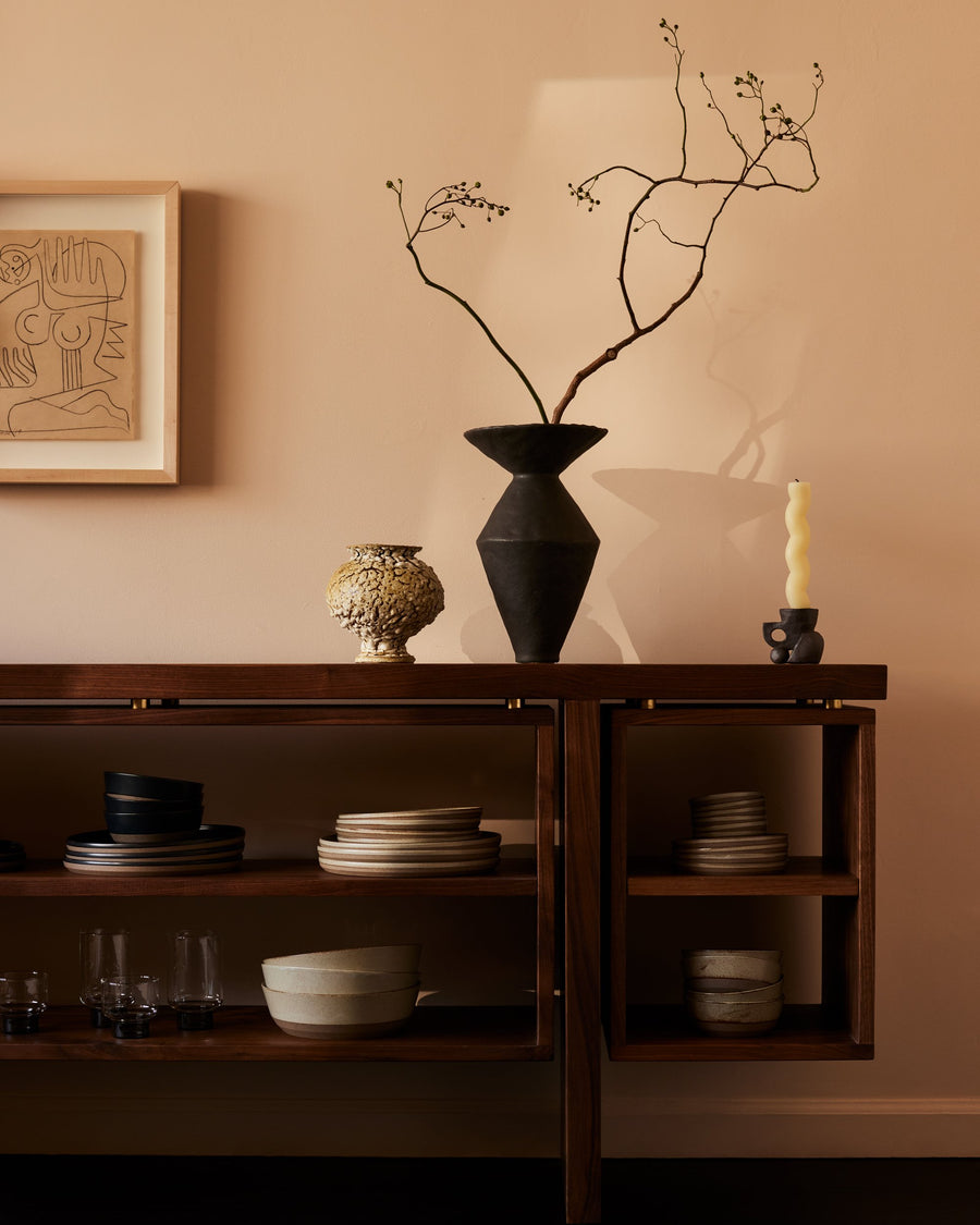 stylized image of walnut wood credenza with free-floating open shelving and bronze fittings