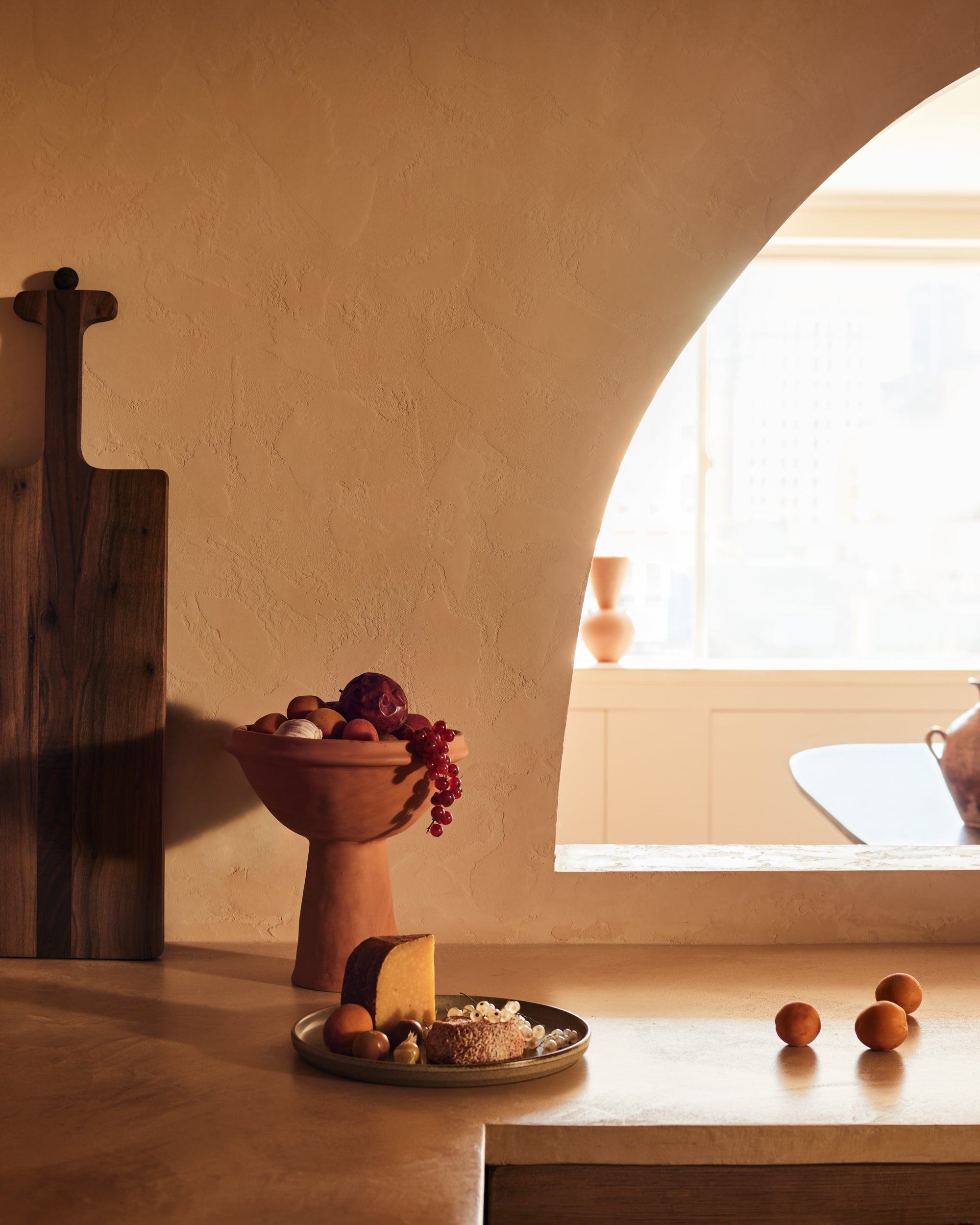 stylized image of terracotta handmade Mediterranean one-piece elevated bowl on cone stoneware fruit platter