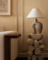 stylized image of sand-colored abstract sculptural ceramic table lamp with ivory rice paper shade
