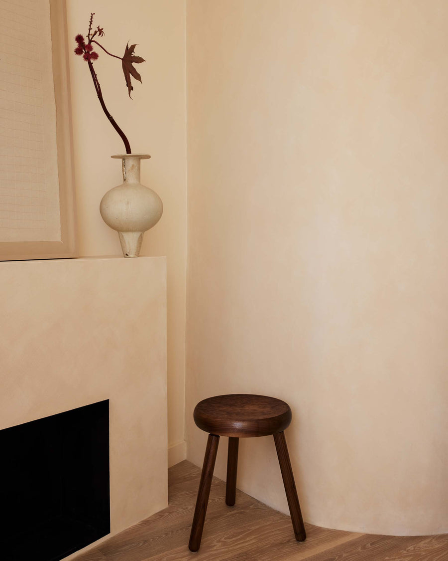 stylized image of elegant minimalist handcrafted solid walnut wood stool with carved textured seat