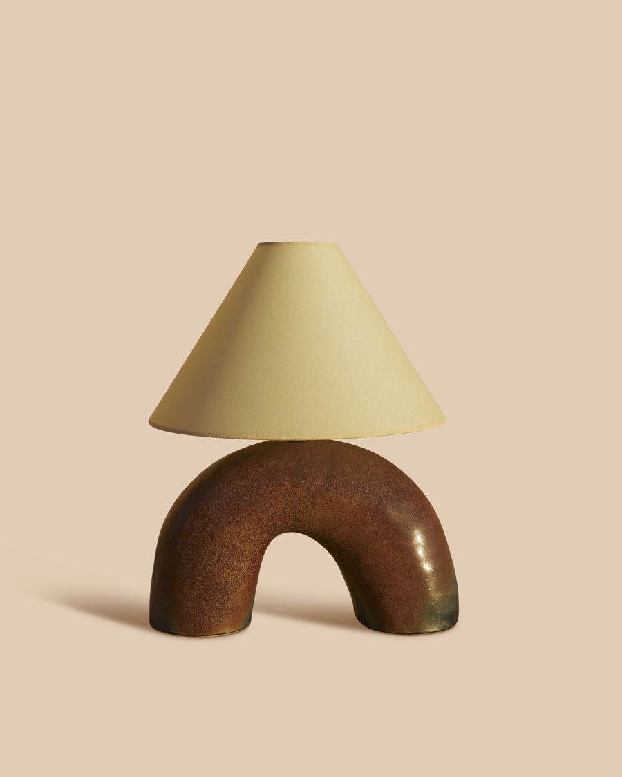 handmade rustic brown ceramic table lamp in a half circle-shaped base with parchment shade