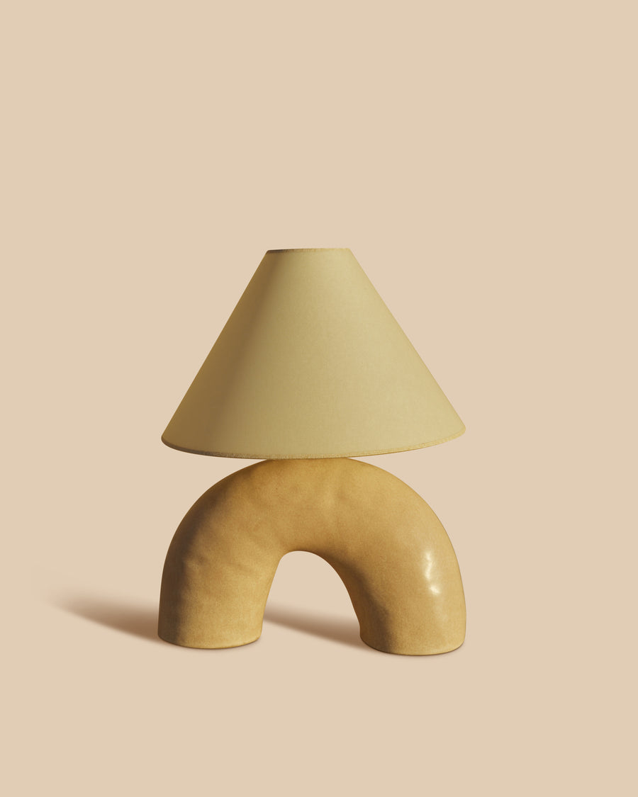 handmade cream ceramic table lamp in a half circle-shaped base with parchment shade