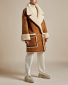 knee-length reversible shearling coat with camel-colored suede, double breasted body, dropped shoulders and generous fold up cuffs on body